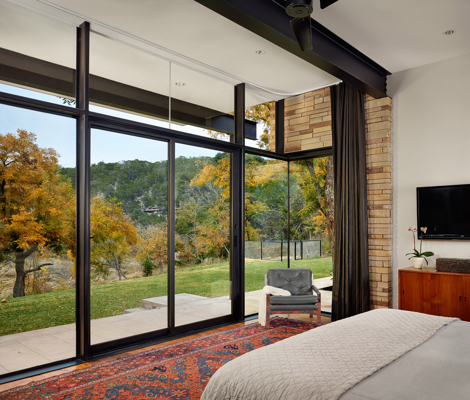 Creekside master bedroom framed in glass and steel.