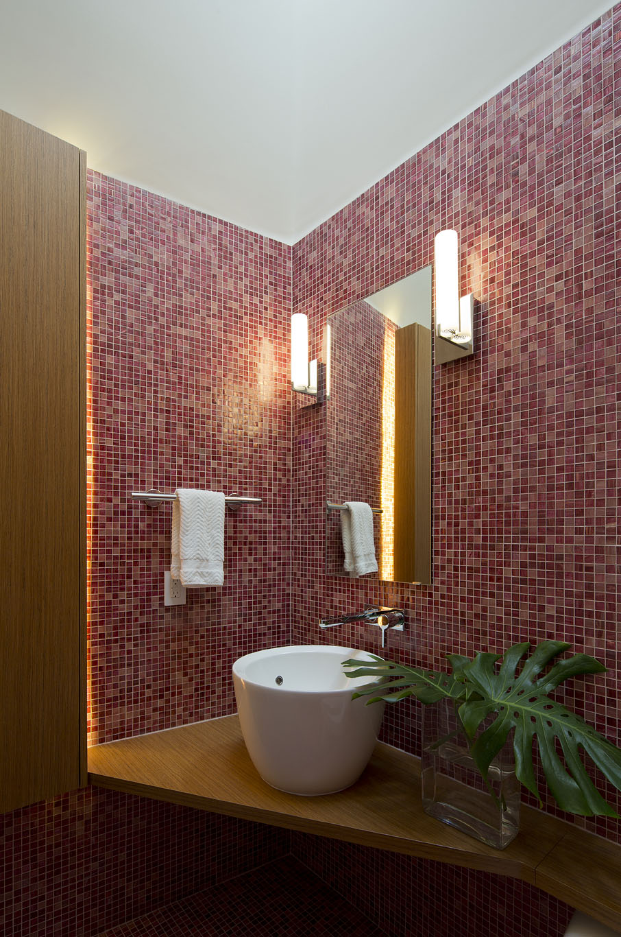 Powder bath welcomes guests with mosaic tile and floating vanity.