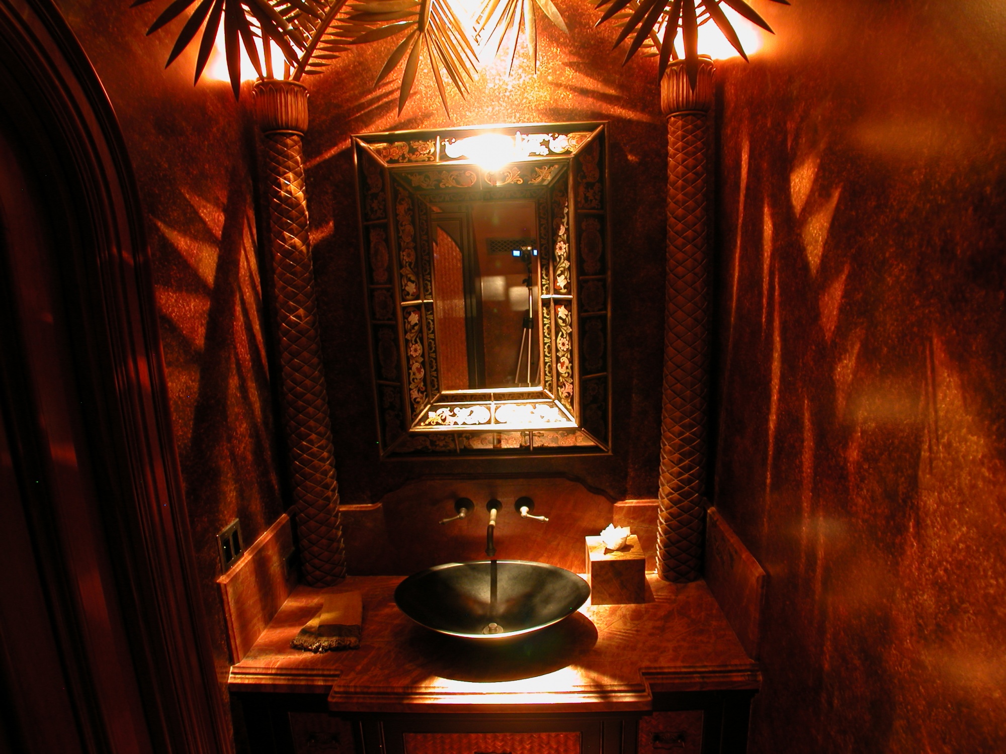Hand carved palm trees are featured in this powder bath.