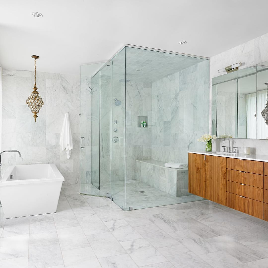 Marble on marble with a splash of walnut makes for a spa-like bathing experience. ⁠
⁠
Built by @foursquarebuilders⁠
⁠
⁠
